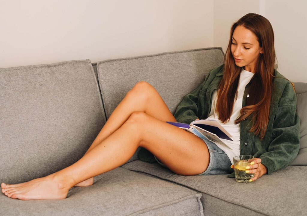 Woman sitting on couch with cup in her hand reading a book about bullying prevention.